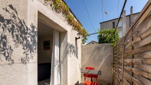 Un piccolo patio esterno con recinzione in legno, una sedia rossa e un tavolo.