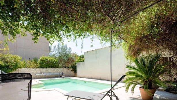 Un giardino sul retro con una piscina, un tavolo e delle sedie.