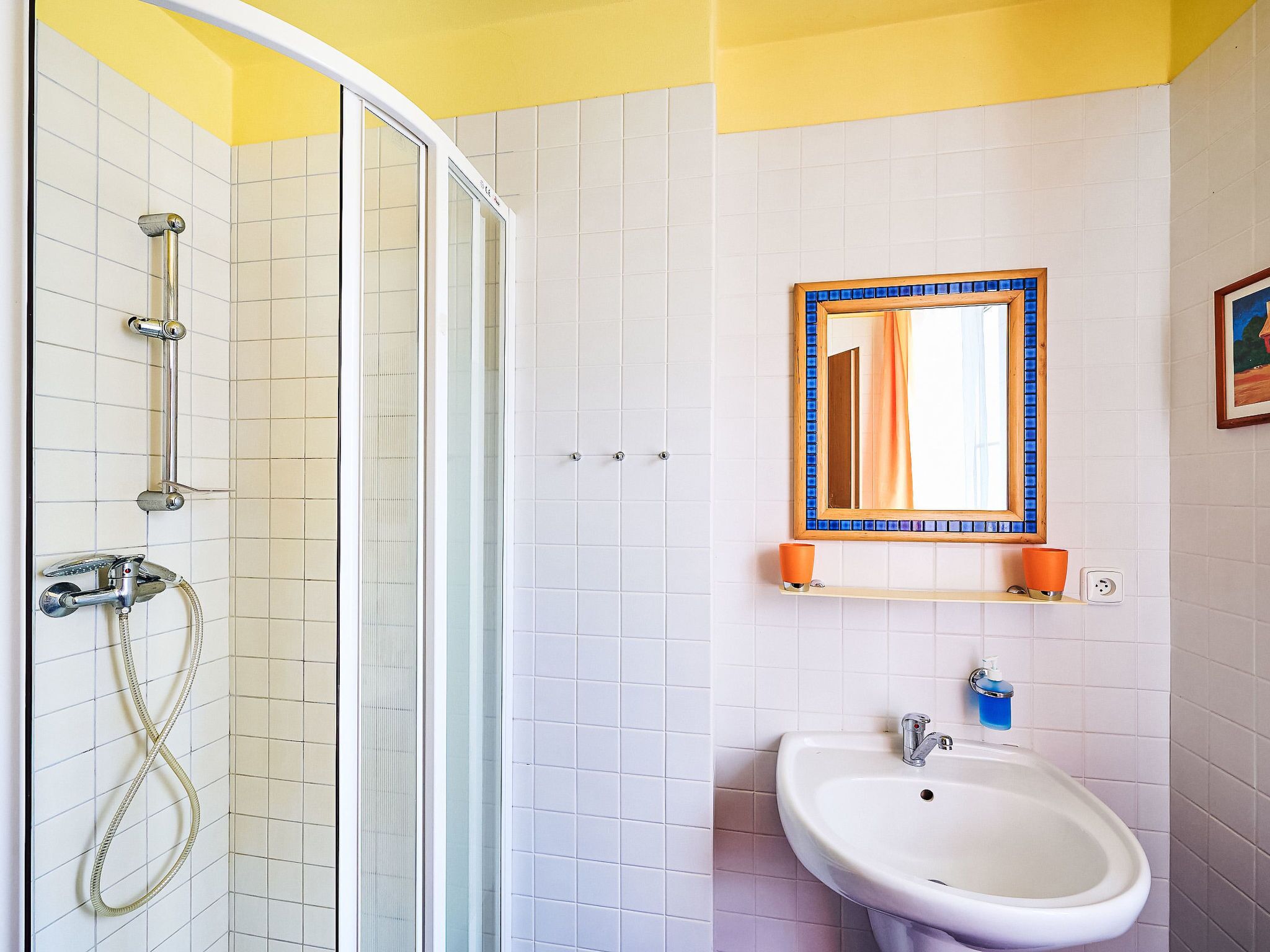 Un baño con ducha, lavamanos y espejo.