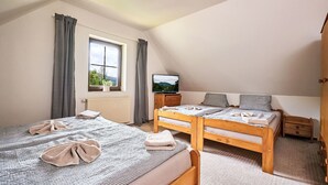A bedroom with two beds, a TV, a window with curtains, and a radiator. - Alice II. by Interhome (Harrachov)