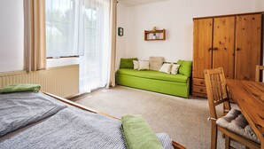 Une pièce avec un canapé vert, une armoire en bois et une petite table avec des chaises.