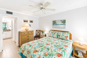 A bedroom with a bed, a nightstand, a chair, a dresser, and a ceiling fan.