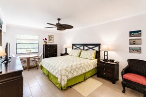 A bedroom with a bed, bedside tables, a desk, a chair, a ceiling fan, and artwork on the wall. - Park Shore Resort-Deluxe Top Floor, BLDGE#332 (Park Shore Resort)