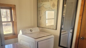 A laundry room with a Samsung washer and dryer, a wooden floor, a large map on the wall, and a door with a mirror. - SPORTSMAN/COUPLES RETREAT. Close to Lakes, Rivers, & Beautiful Ludington (Custer)