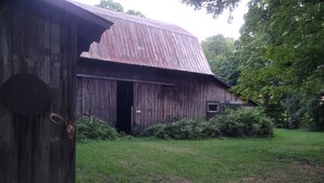 A rustic wooden barn with a slanted roof, a door, and a small window. - SPORTSMAN/COUPLES RETREAT. Close to Lakes, Rivers, & Beautiful Ludington (Custer)