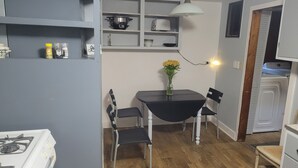 A compact kitchen with a stove, a dining table with chairs, and a shelf with kitchen items. - SPORTSMAN/COUPLES RETREAT. Close to Lakes, Rivers, & Beautiful Ludington (Custer)