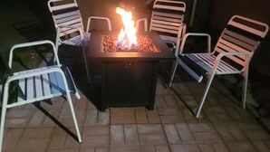 A square outdoor seating area with a built-in fire feature, surrounded by metal chairs. - SPORTSMAN/COUPLES RETREAT. Close to Lakes, Rivers, & Beautiful Ludington (Custer)