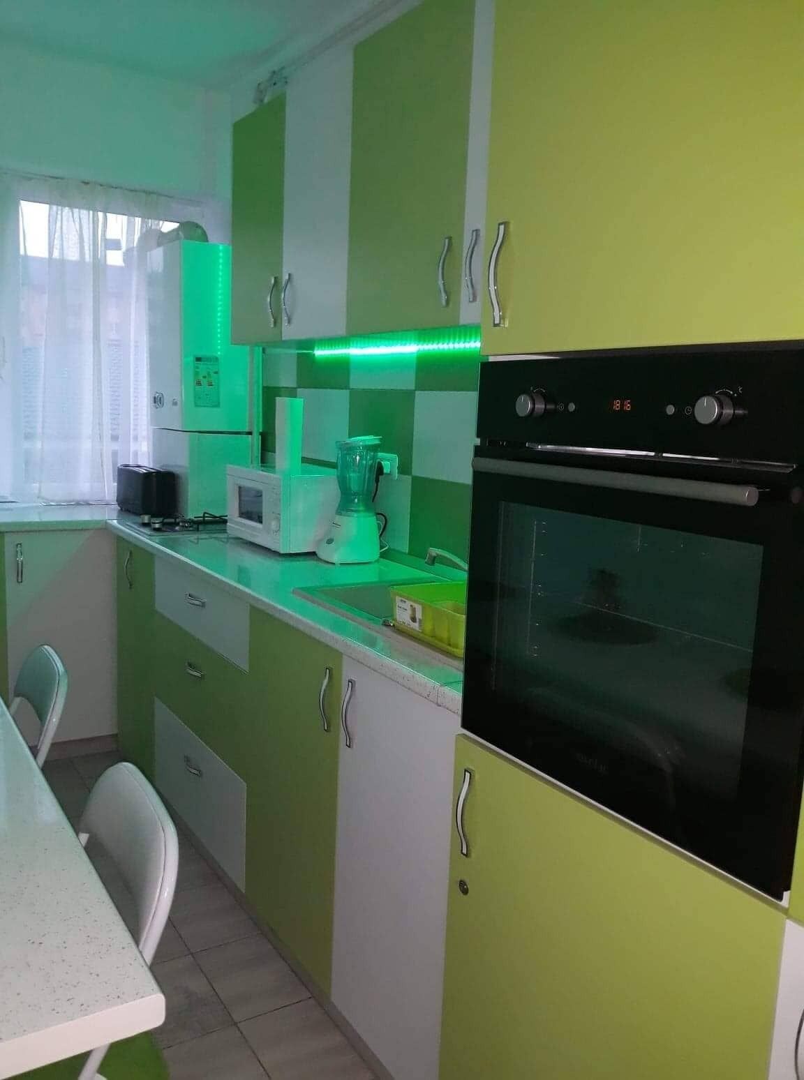 Une cuisine avec des meubles de couleur verte, un four à micro-ondes, un mixeur et un four traditionnel.