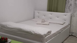 A neatly made bed with white bedding and a green bedside table. - Stunning Green Studio 43 (Chiajna)