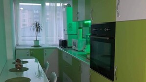 A compact kitchen with a dining area, featuring a microwave, oven, and green cabinets. - Stunning Green Studio 43 (Chiajna)