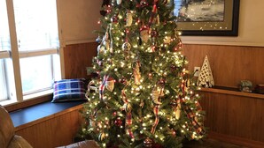 A living room with a Christmas tree, a brown leather sofa, and a window with blinds. - English Cottage near Branson Attractions (Lampe)