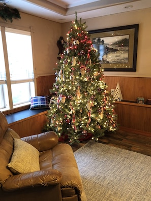 A living room with a Christmas tree, a brown leather sofa, and a window with blinds. - English Cottage near Branson Attractions (Lampe)