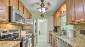 A kitchen with granite countertops, stainless steel appliances, wooden cabinets, and a ceiling fan.
