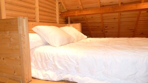 Une chambre mansardée avec un cadre en bois, comprenant un lit et des oreillers.