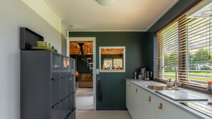 A compact kitchen with a built-in refrigerator, a sink, and a window with blinds.