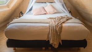 A cozy, triangular bedroom with a canopy bed, wooden walls, and a skylight.