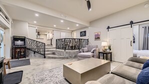 A spacious living area with a sofa, coffee table, and a staircase with a decorative railing.