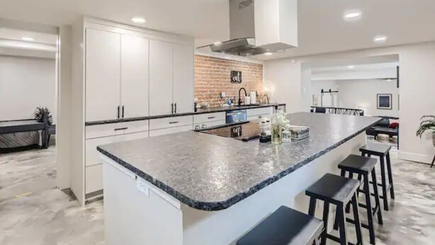 A modern kitchen with white cabinets, a granite countertop, and a central island with bar stools.