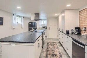 Modern kitchen with oven, microwave, and stainless steel range hood, plus a coffee maker and patterned rug.