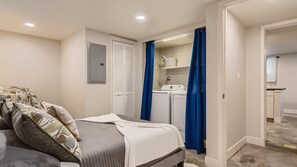Cozy retreat with a neatly made bed and convenient laundry facilities.