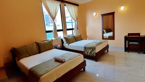 A hotel room with two beds, a desk, and a chair. - Hostal California Inn (Guayaquil)