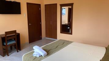 Een slaapkamer met een bed, een bureau en een kledingkast.