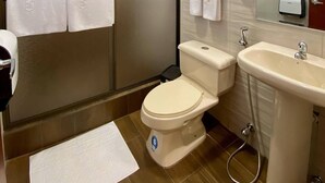 A modern bathroom with a toilet, sink, and shower. There are towels hanging on the wall and a mirror above the sink. - Hostal California Inn (Guayaquil)