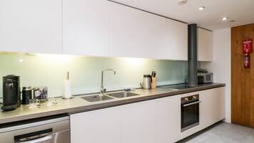 Una cocina moderna con gabinetes blancos, electrodomésticos de acero inoxidable y encimera gris.
