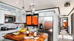 Eine moderne Küche mit einer Holztheke, Edelstahlgeräten und einer leuchtend orangefarbenen Wand.