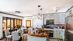 Eine moderne Küche mit einer Holztischinsel, Edelstahlgeräten und einem Essbereich mit Tisch und Stühlen.