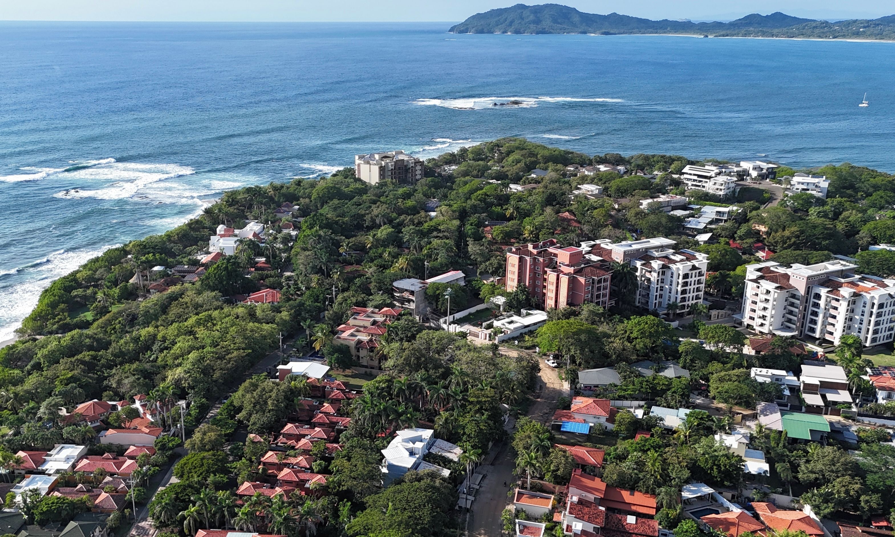 A coastal residential area with buildings, roads, and a beach.