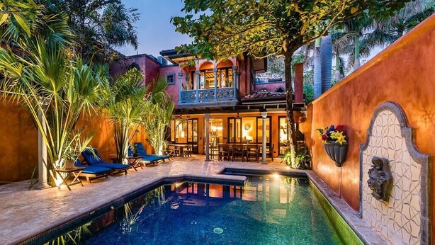 Un espace piscine comprenant des chaises longues, une petite piscine et un bâtiment doté d’un balcon.