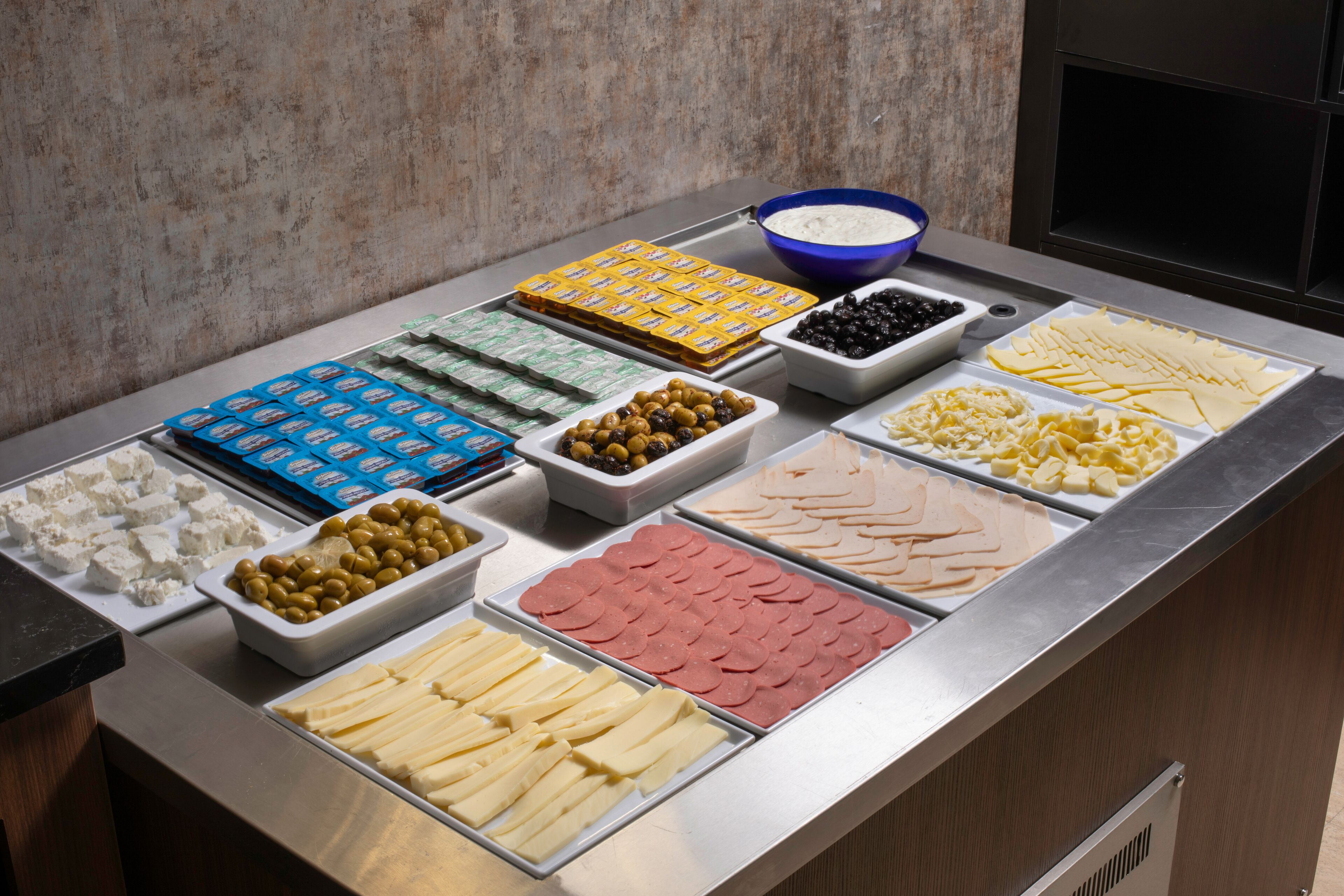 A buffet with various food items including cheese, olives, and sliced meats.