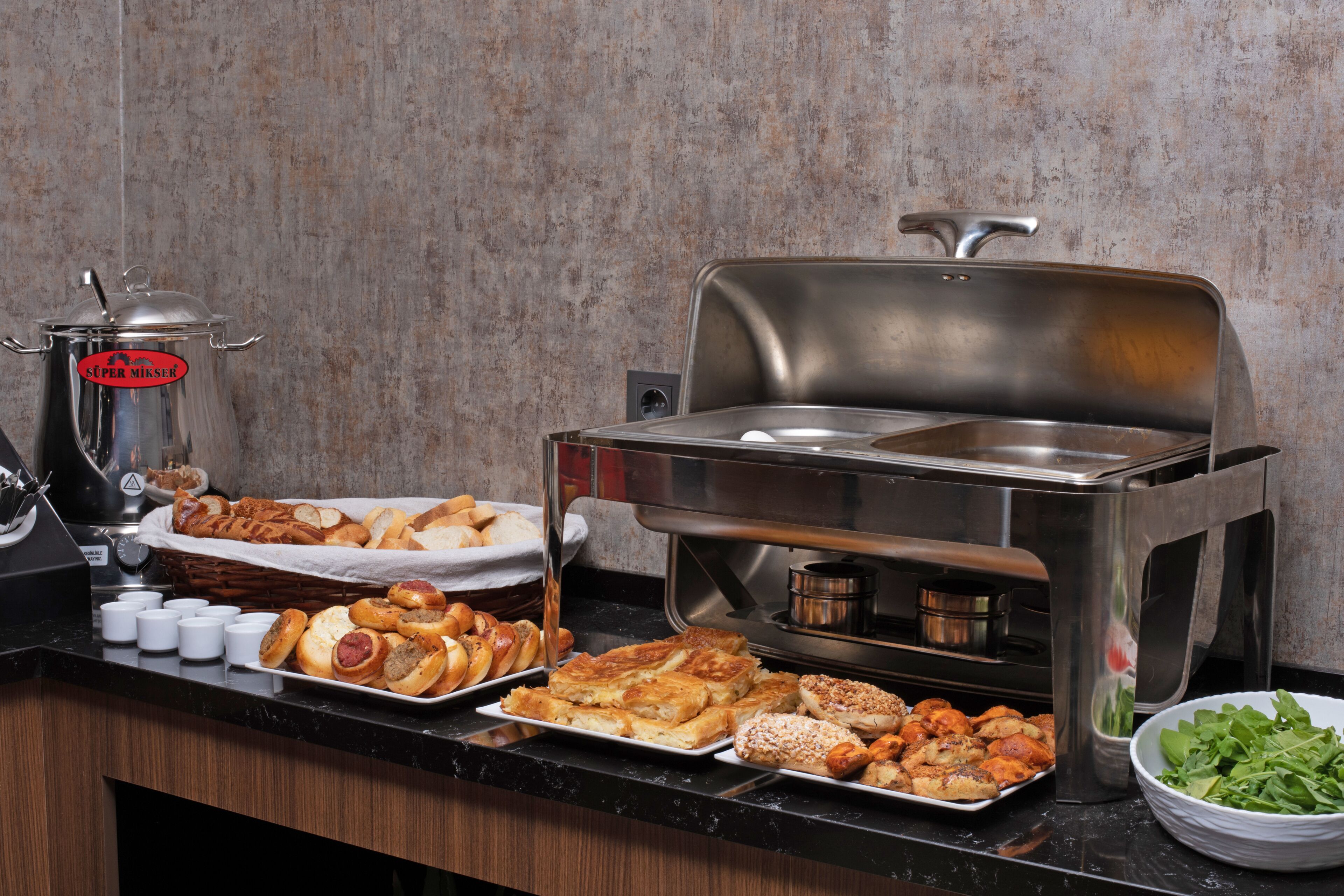 Un buffet proposant divers plats, un coin café et un saladier.