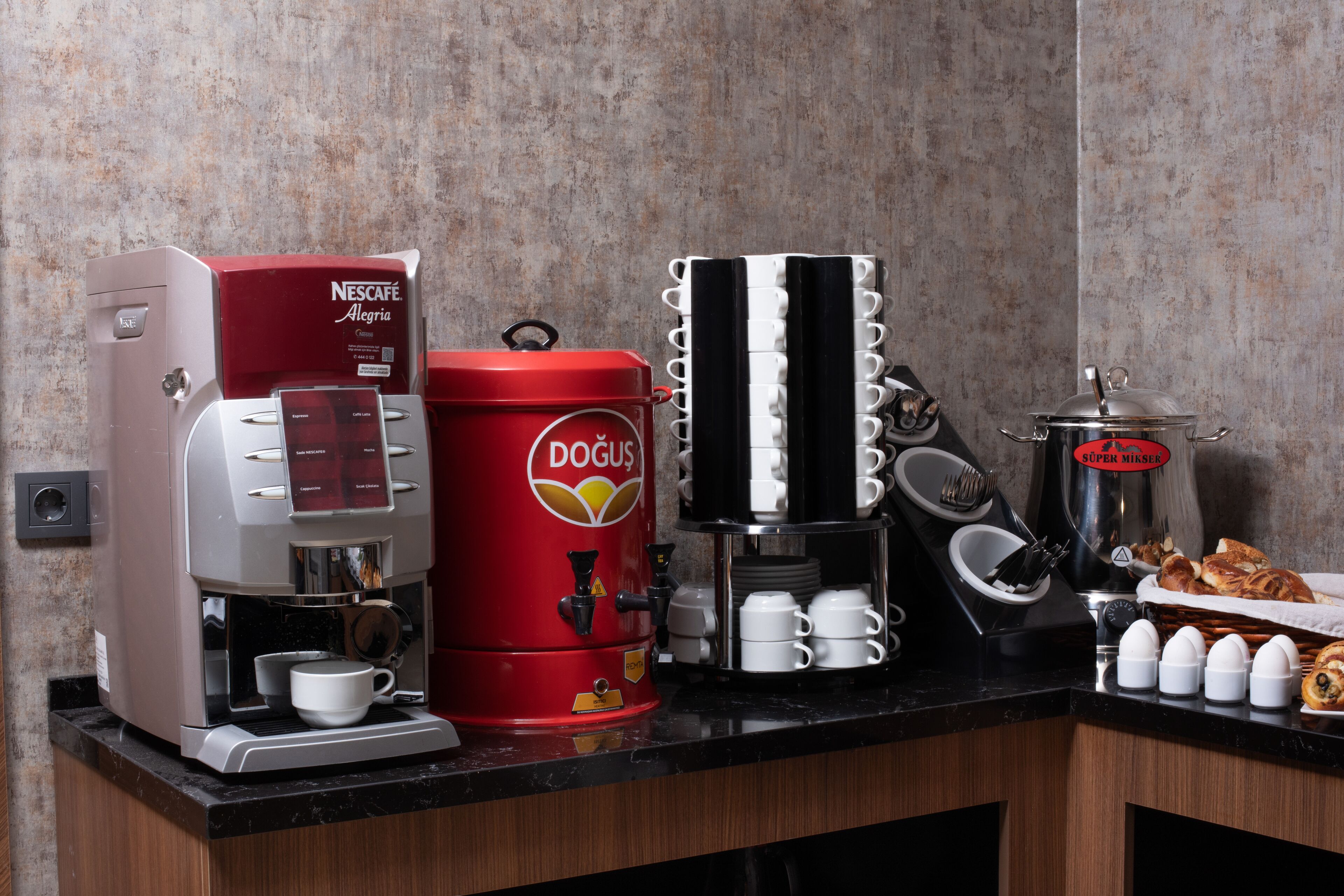 Una estación de café con una máquina de café Nescafé, un dispensador de café Docu y una jarra de café.