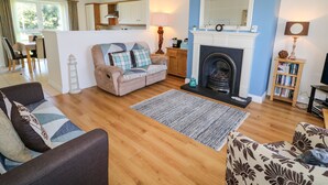 A living room with a fireplace, a sofa, a coffee table, and a bookshelf. - 4 The Cloisters (Bushmills)