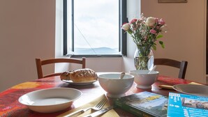 Et spisebord med en croissant, skåle, en vase med blomster og et magasin.