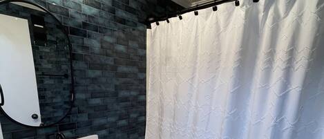 A bathroom with a white sink, a toilet, a mirror, and a shower curtain.