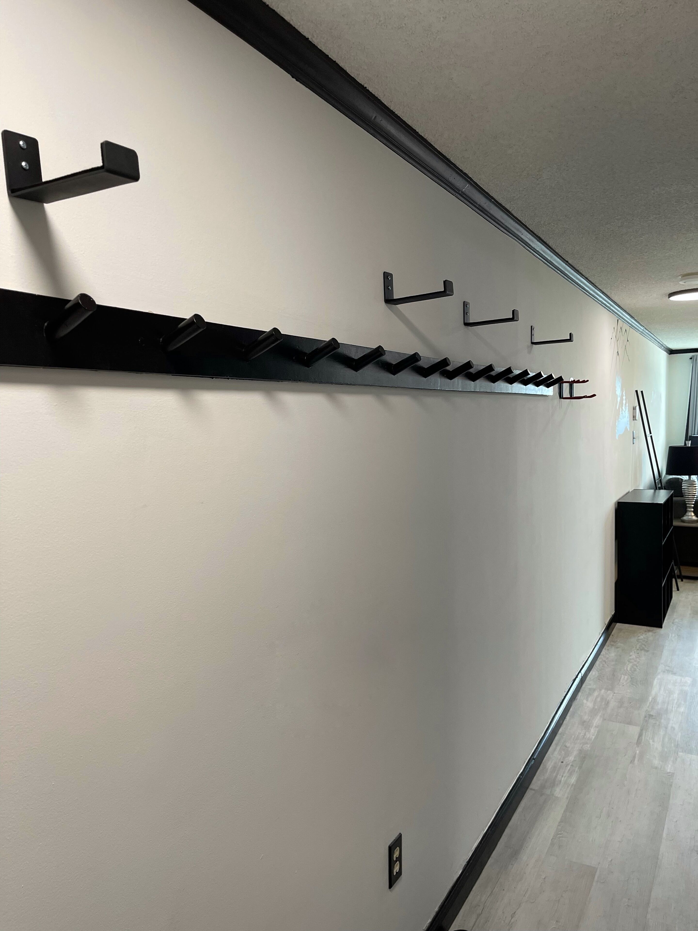 A hallway with a black metal rack for coats and a black cabinet.