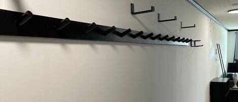A hallway with a black metal rack for coats and a black cabinet.