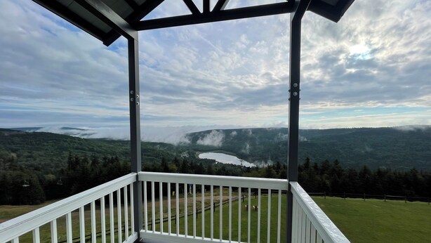 Un espace extérieur abrité offrant une vue sur un lac et les collines environnantes.