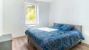 A bedroom with a bed, a window, and a small desk.
