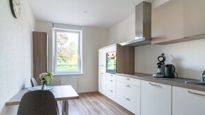 A modern kitchen with a dining table, chairs, and a window.