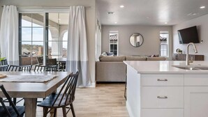 A modern kitchen with a large island, white cabinetry, and a flat-screen TV mounted above the island. - VACATION STATION, PICKLEBALL, KAYAKS, WIGGLECARS, PING PONG, FOOSBALL, BBQ (Washington)