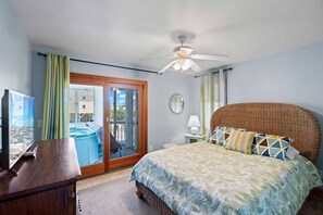A bedroom with a bed, a desk, a window with curtains, a ceiling fan, and a view of a swimming pool. - Oceanview Home with Private Pool, Hot Tub, Game Room, and Nearby Beach Access (Avon)