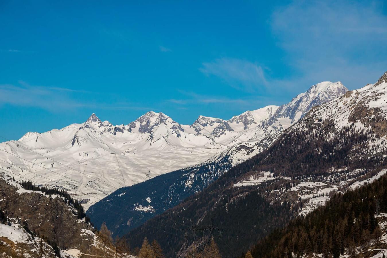 A mountain landscape with snow-covered peaks and a clear blue sky.