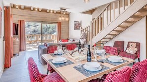 A dining area with a wooden table set for four, a staircase, and a view of the outdoors.