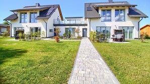 Une maison moderne à deux étages, dotée d’une allée pavée, de panneaux solaires et d’une pelouse bien entretenue.