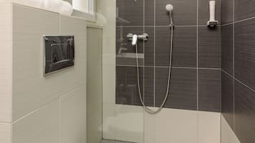 Un baño moderno con inodoro, ducha con cabezal de ducha manual y toallero.