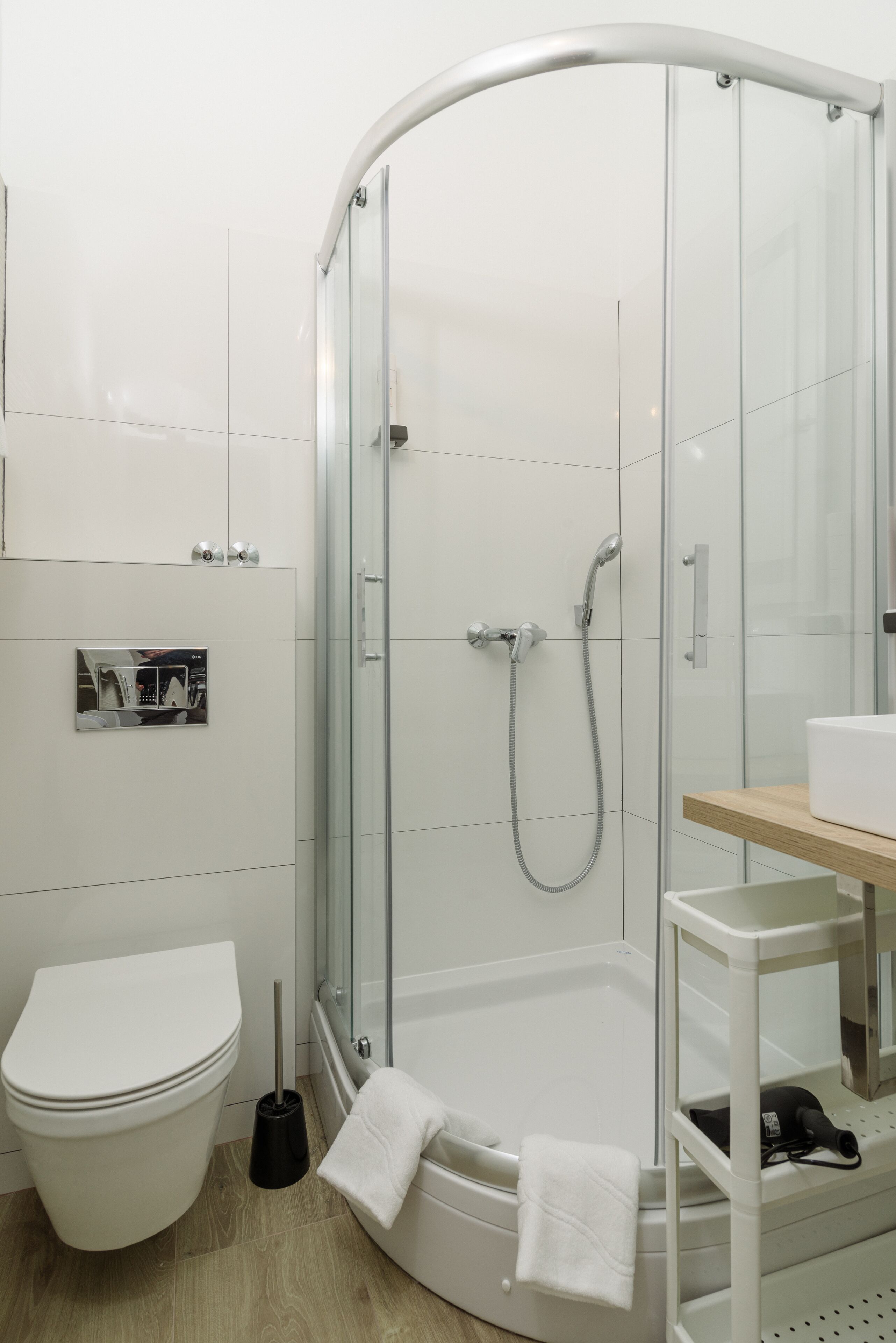 Ein modernes Badezimmer mit einer gläsernen Dusche, einer weißen Toilette und einem Holzkosmetikschrank.